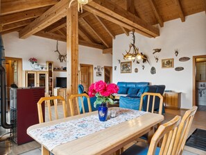 A dining area with a wooden table, chairs, and a vase of flowers.