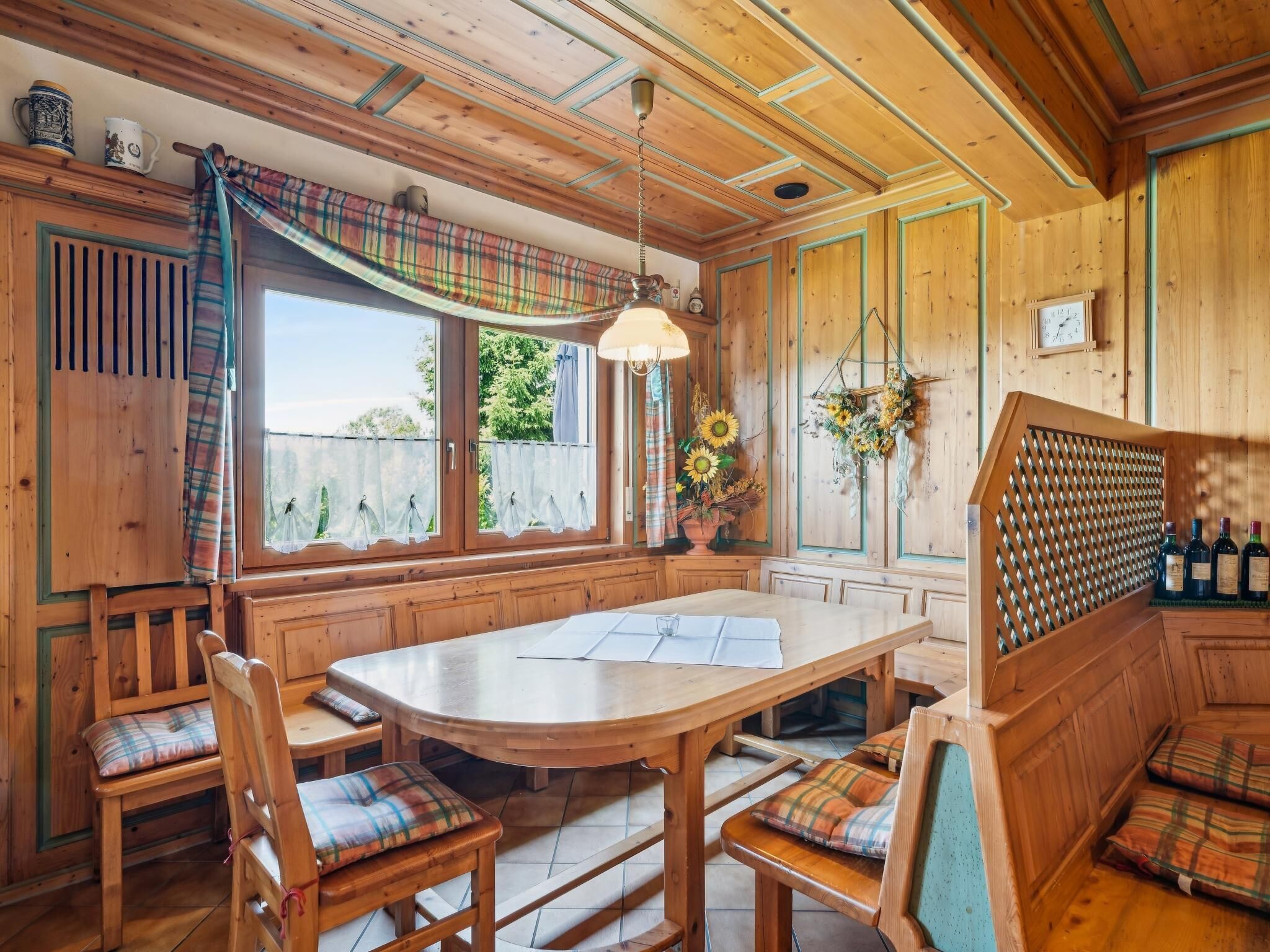 Een houten interieur met een centrale tafel, banken en een hanglamp.
