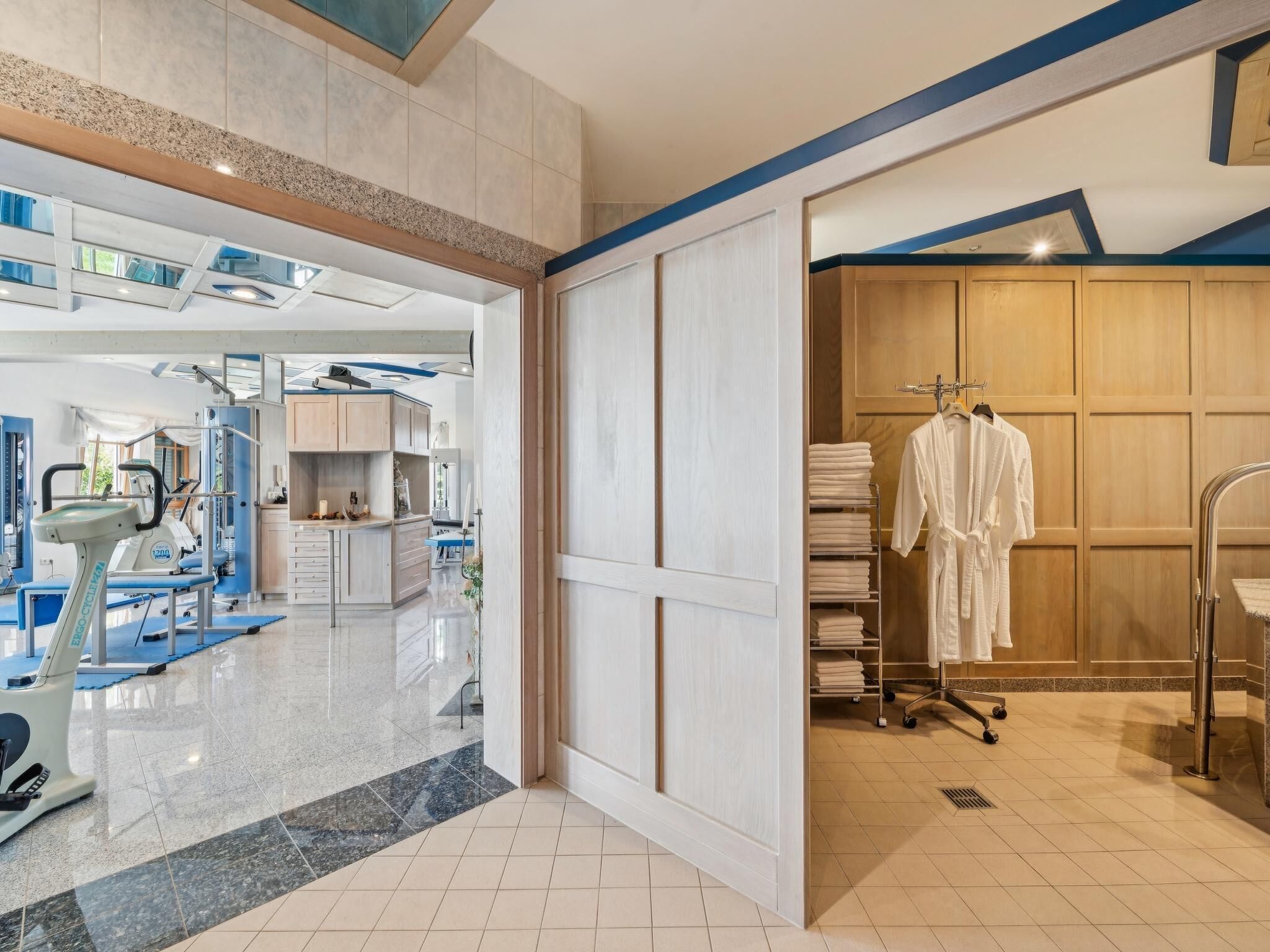 Ein Hotelzimmer mit Fitnessbereich, einem großen Spiegel und einem Schrank mit Bademänteln.