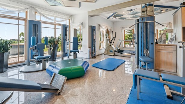 A spacious gym with exercise equipment, large windows, and a view of the outdoors. - Holiday apartment in the Bavarian Forest (Waldkirchen)