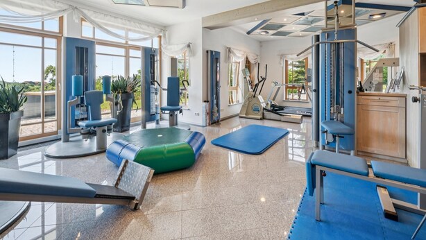 A spacious gym with exercise equipment, large windows, and a high ceiling. - Quiet holiday apartment in the Bavarian Forest (Waldkirchen)