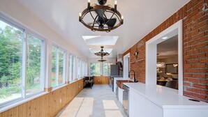 A modern kitchen with large windows, a brick accent wall, and a central island.