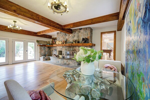 A spacious living room with a stone fireplace, wooden beams, and a glass coffee table. - Privacy Magical Forest Cottage 30+ Party Room,  Disco KTV (Uxbridge)