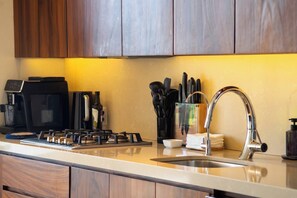 A kitchen with a coffee maker, stove, sink, and knife set.