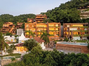 A resort with multiple buildings, a swimming pool, and lush greenery.