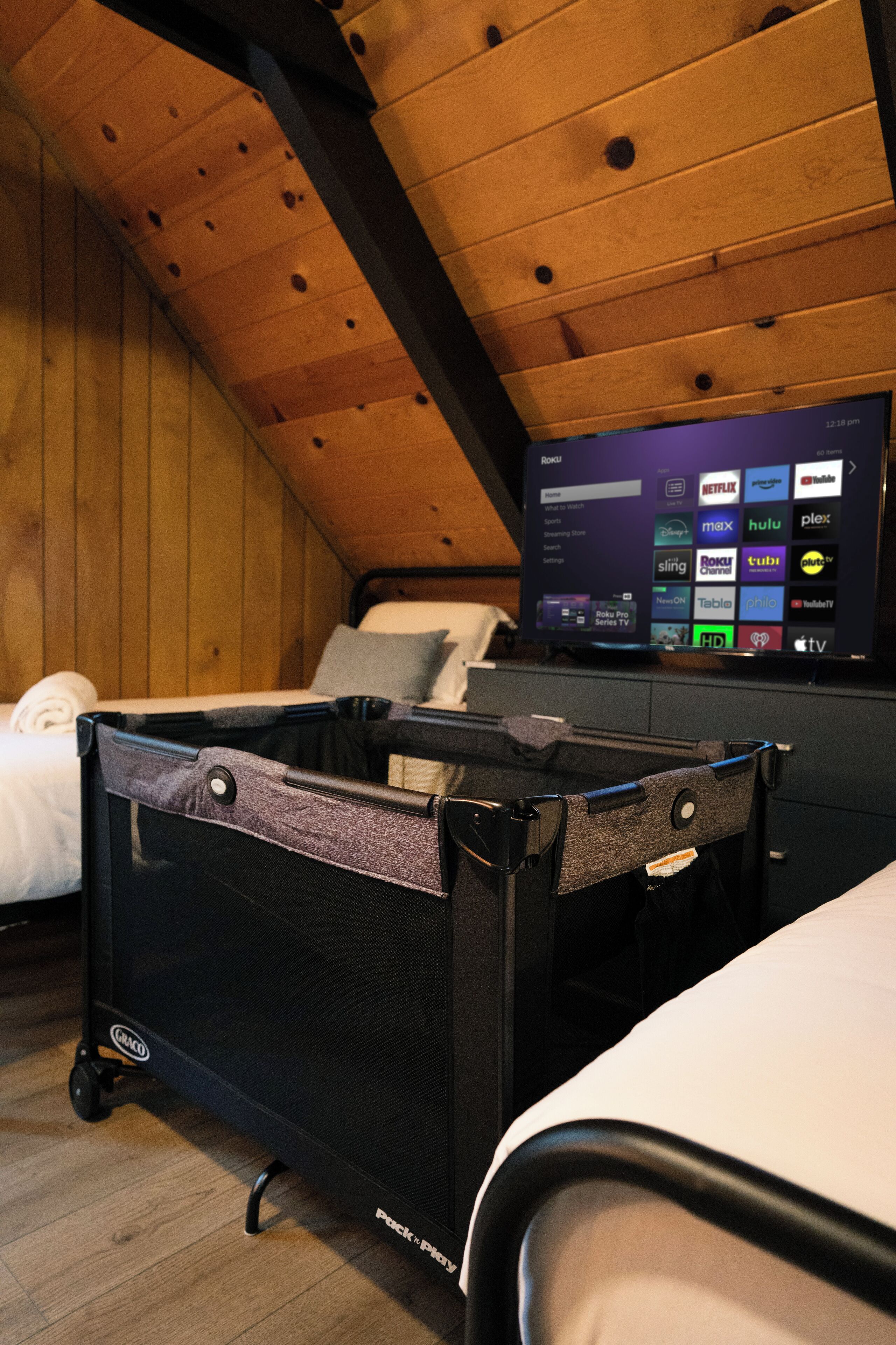 A compact room with a bed, a small desk, and a television displaying streaming services.