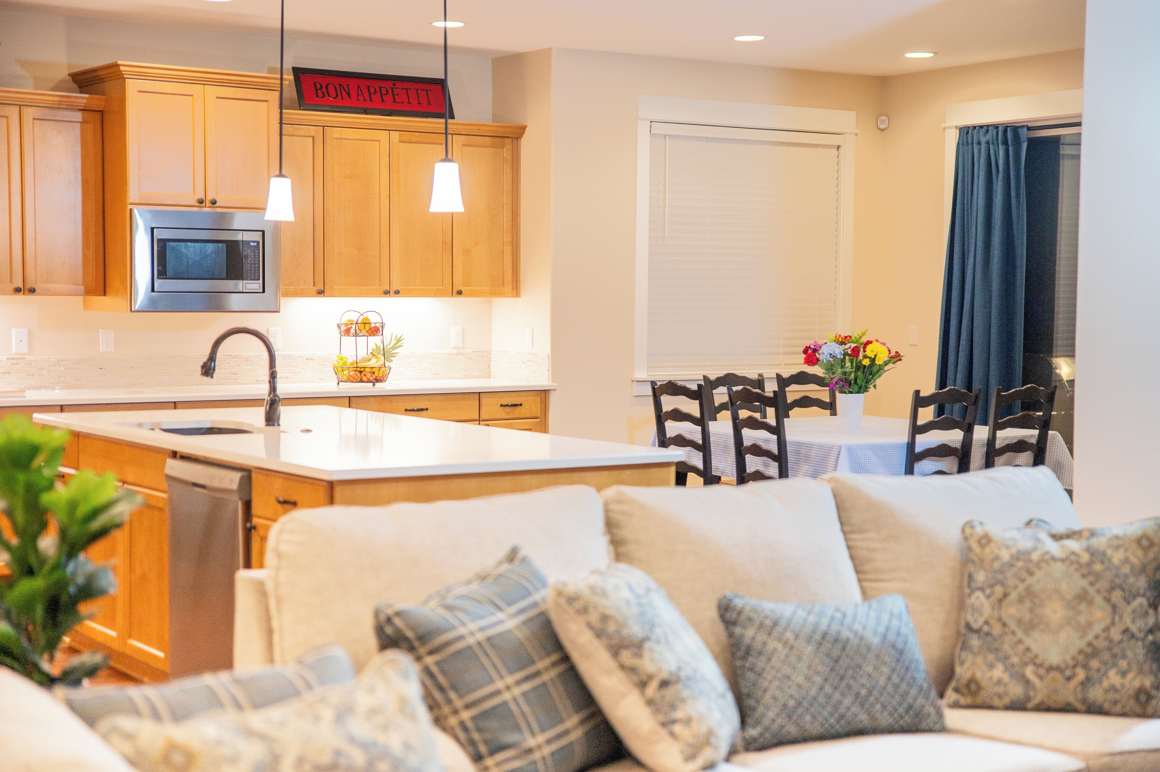 A modern kitchen with wooden cabinets, a built-in microwave, and a sign above the cabinets.