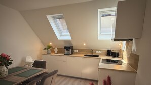 A compact kitchen with a dining area, a coffee machine, and a radiator. - Spacious Apartment with Lake View, Shared Terrace and Wi-Fi (Feldberger Seenlandschaft)