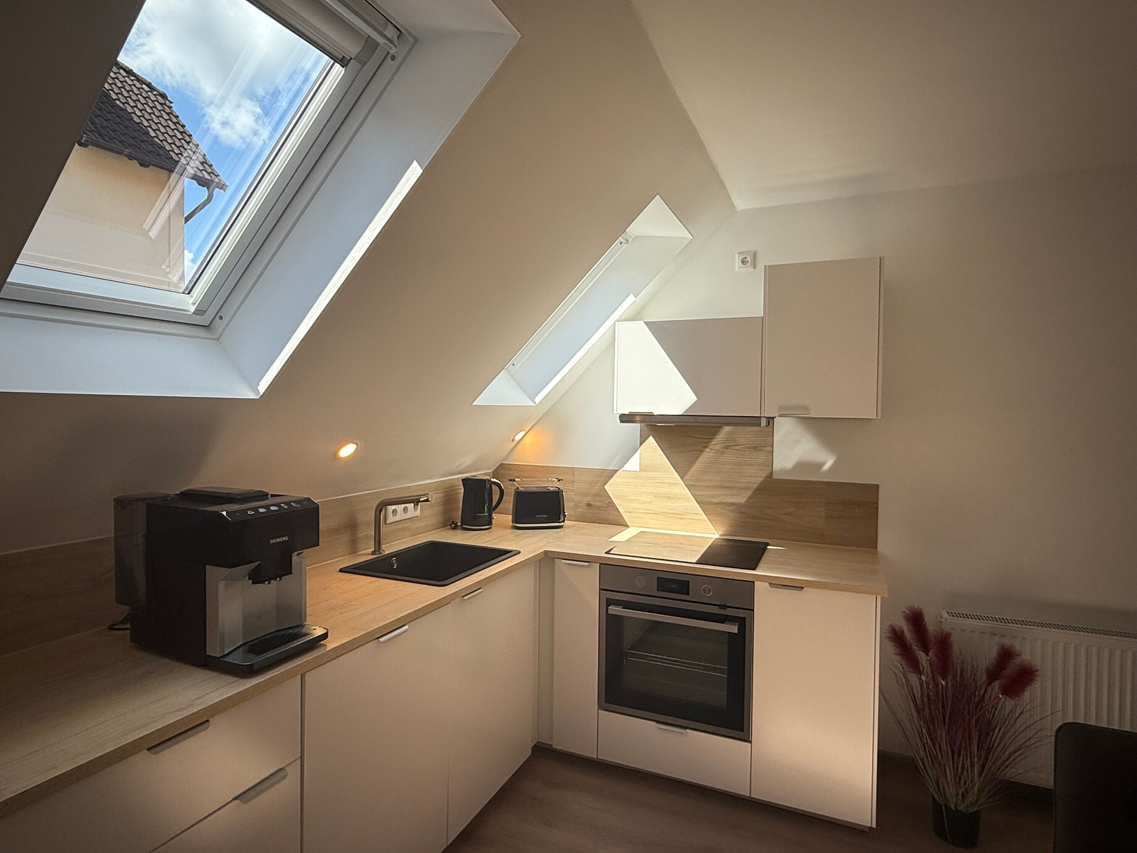 A modern kitchen with a skylight, built-in oven, and a coffee maker.