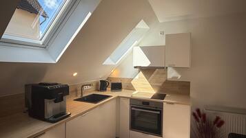 A modern kitchen with a skylight, built-in oven, and a coffee maker.