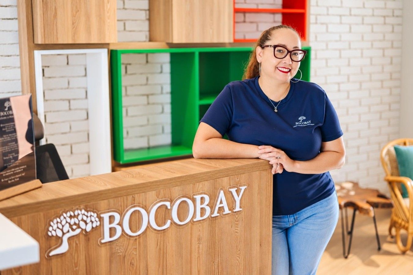 Una mesa de recepción con el nombre 'BOCOBAY' y un logo que muestra un árbol.