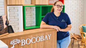 Una mesa de recepción con el nombre 'BOCOBAY' y un logo que muestra un árbol.