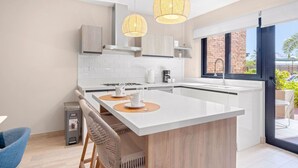 Une cuisine moderne dotée d’un îlot central, de meubles blancs et d’une grande fenêtre.