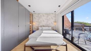 A modern bedroom with a large bed, a wardrobe, and a view of a pool and outdoor area.