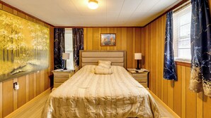A bedroom with a bed, nightstands, a painting, and curtains. - No Pet Fee! Peaceful Escape at Towner Properties (Langston)