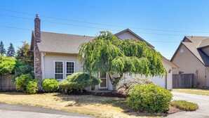 A single-story house with a chimney, a front yard with various shrubs, and a clear blue sky. - Private Outdoor Space 9 Mi to Downtown Vancouver! (Vancouver)