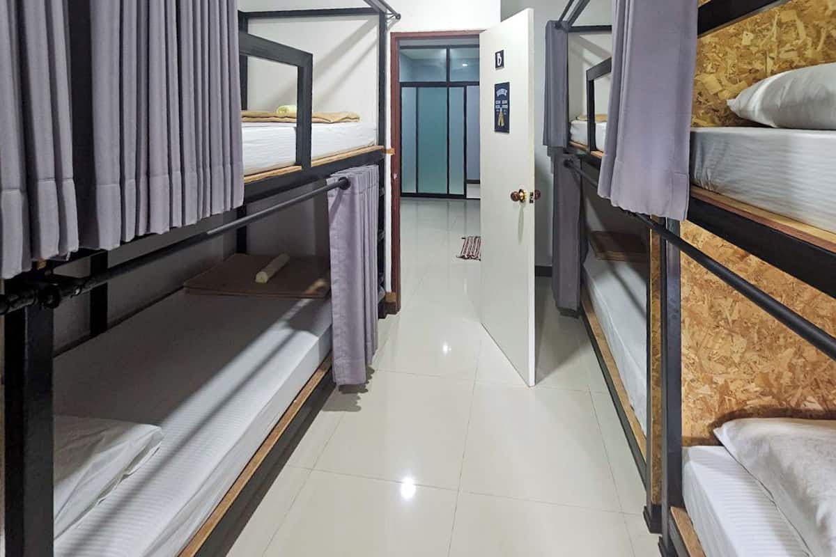 A dormitory room with bunk beds, a door with a sign, and a tiled floor.