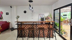 Una cocina moderna con pared de ladrillo, mostrador de bar de madera y cuatro taburetes. Hay un reloj y un letrero en la pared, y una planta en maceta sobre el mostrador.