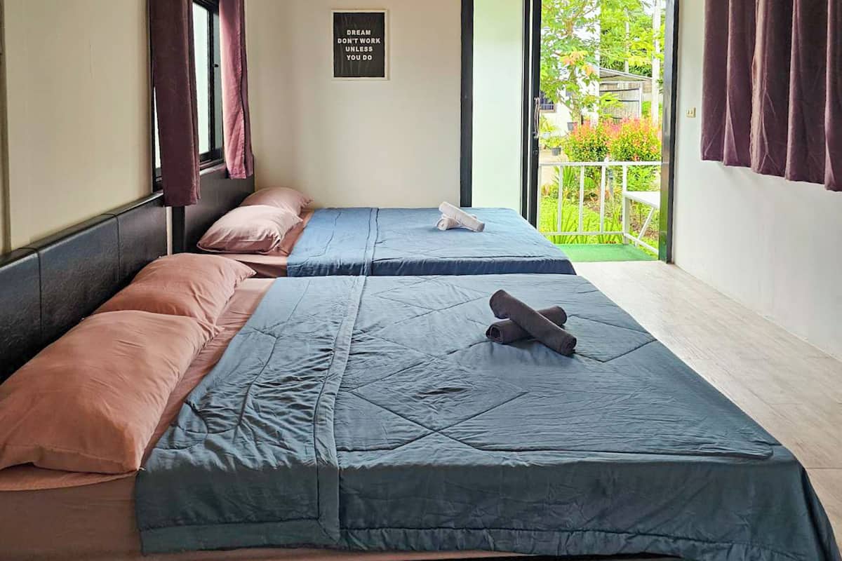 A room with two beds, each with a blue and pink bedspread, and a motivational poster on the wall.