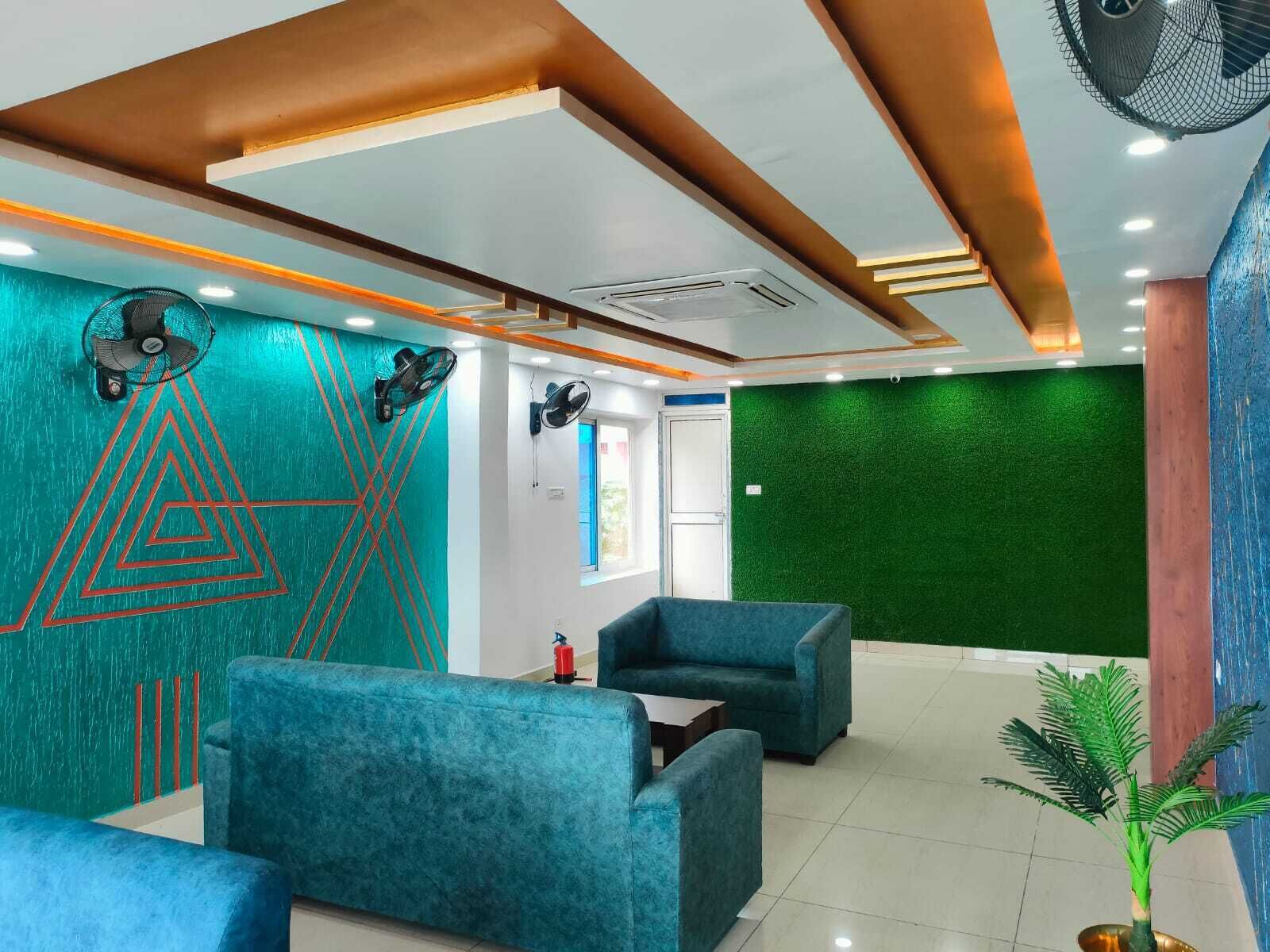 Un espace d’attente moderne avec des murs de couleur turquoise, des œuvres d’art géométriques et des sièges bleus recouverts de tissu.