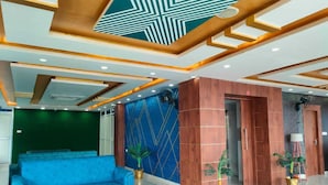 Een moderne lobby met een blauwe bank, een glazen salontafel en een behang met een patroon.