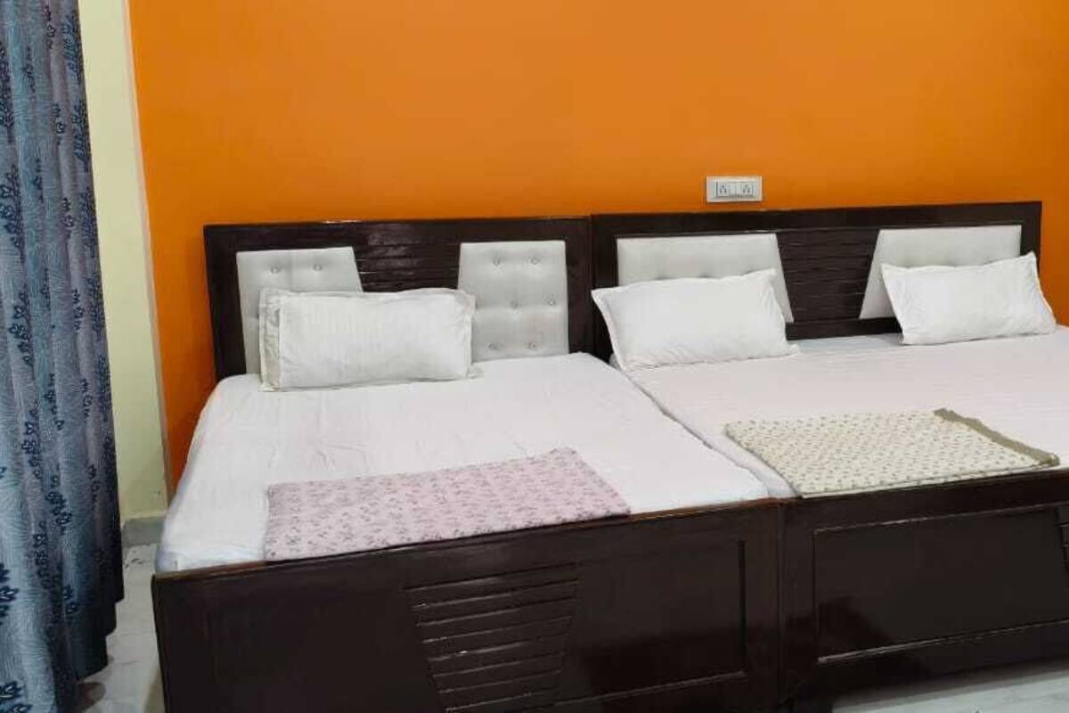 Ein Doppelbett mit dunklem Holzgestell und weißer Bettwäsche vor einer orangefarbenen Wand.