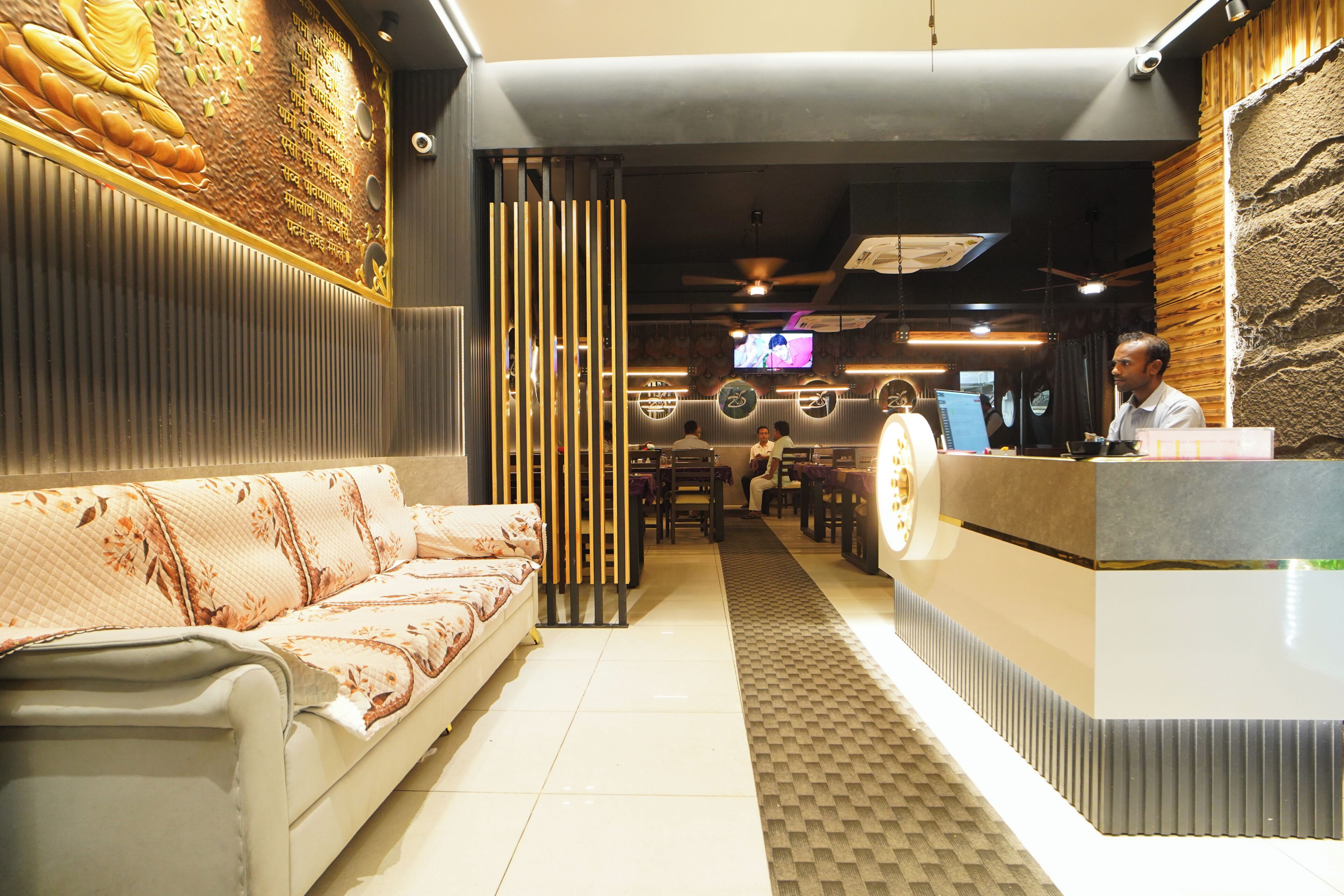 A hotel reception area with a sofa, a reception desk, and a television screen.