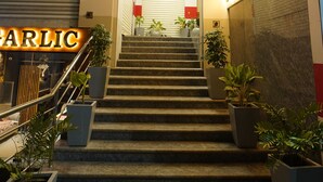 A hotel entrance with a staircase leading up to the lobby, a sign for a bank branch, and a sign for a restaurant.