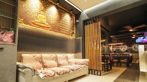 A modern interior with a sofa, a decorative wall, and a dining area.