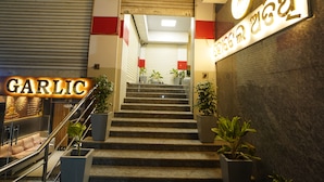 A staircase with potted plants, a sign reading "GARLIC", and a clock on the wall.