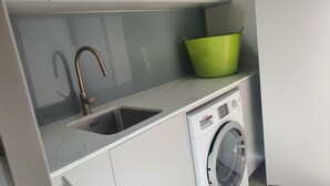 A kitchen with a sink, faucet, and a washing machine.