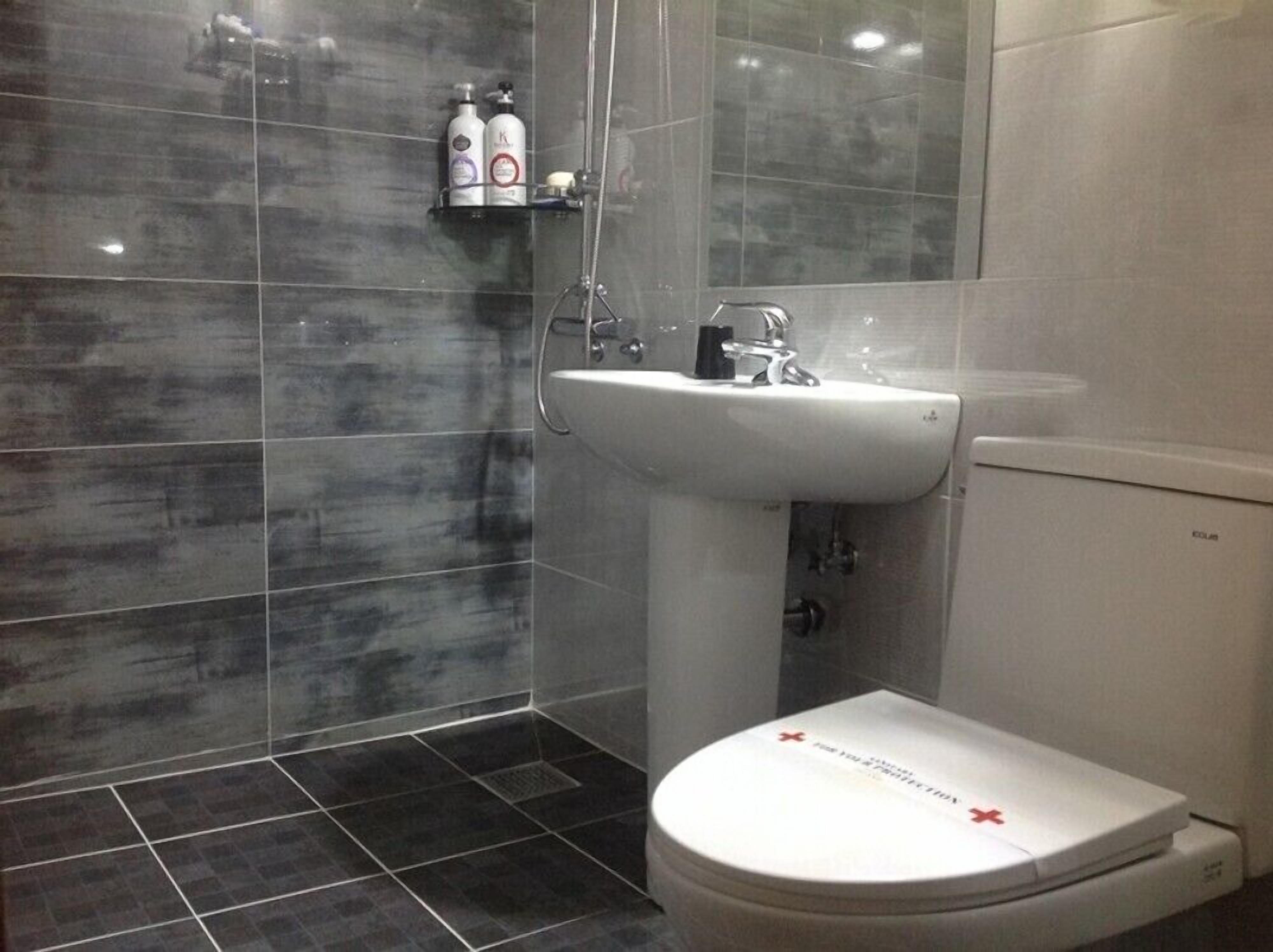 A modern bathroom with a white sink, a toilet, and a shower area.