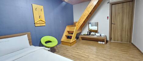 Un dormitorio con una cama, una silla verde, un escritorio de madera, un espejo, una escalera y una puerta.