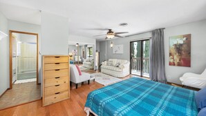 A bedroom with a bed, a dresser, a chair, a sofa, and a ceiling fan.