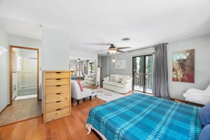 A bedroom with a bed, a dresser, a chair, a sofa, and a ceiling fan.
