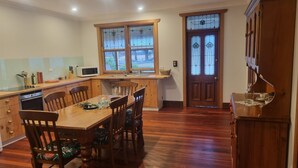 Una cocina con armarios de madera, una mesa de comedor con sillas, un microondas y una ventana con vistas a árboles.