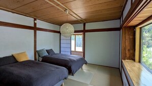 A room with two beds, a wooden ceiling, a window, and a traditional hanging light fixture.