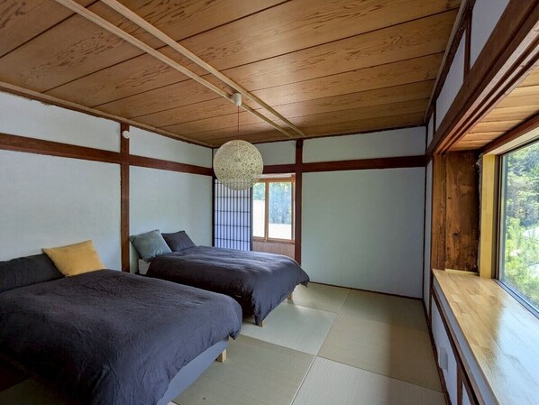 Une chambre avec deux lits, un plafond en bois, une fenêtre et un luminaire traditionnel suspendu au plafond.