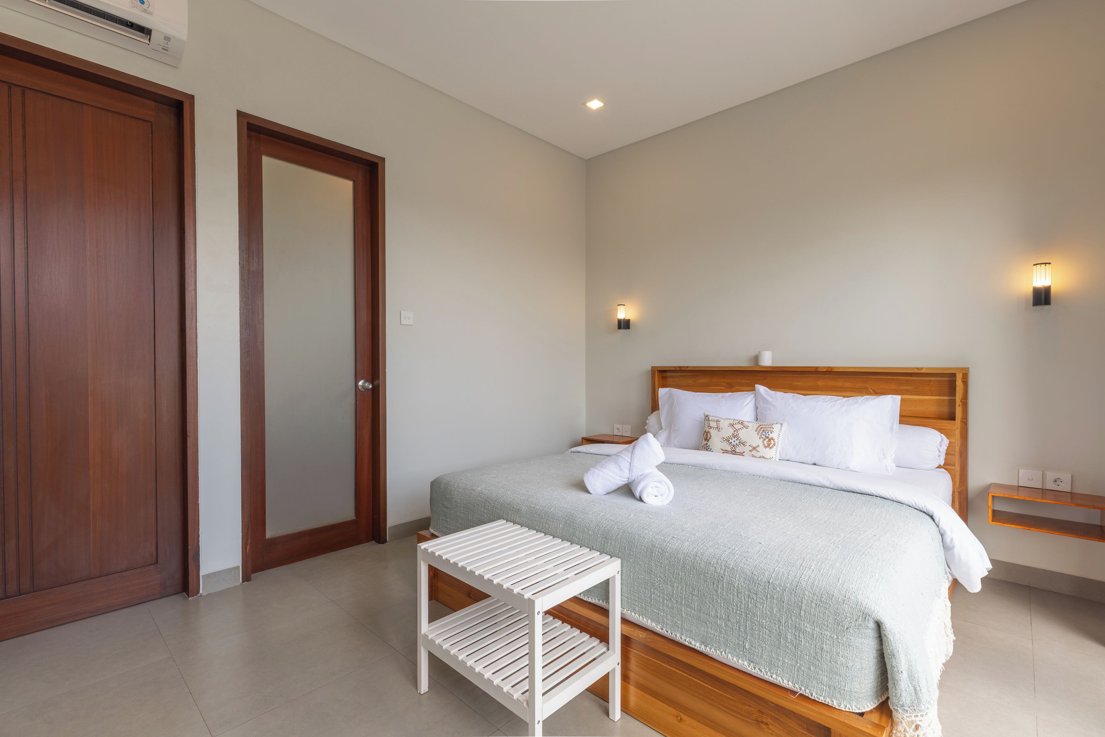 A bedroom with a wooden bed, a white bedside table, and a nightstand.