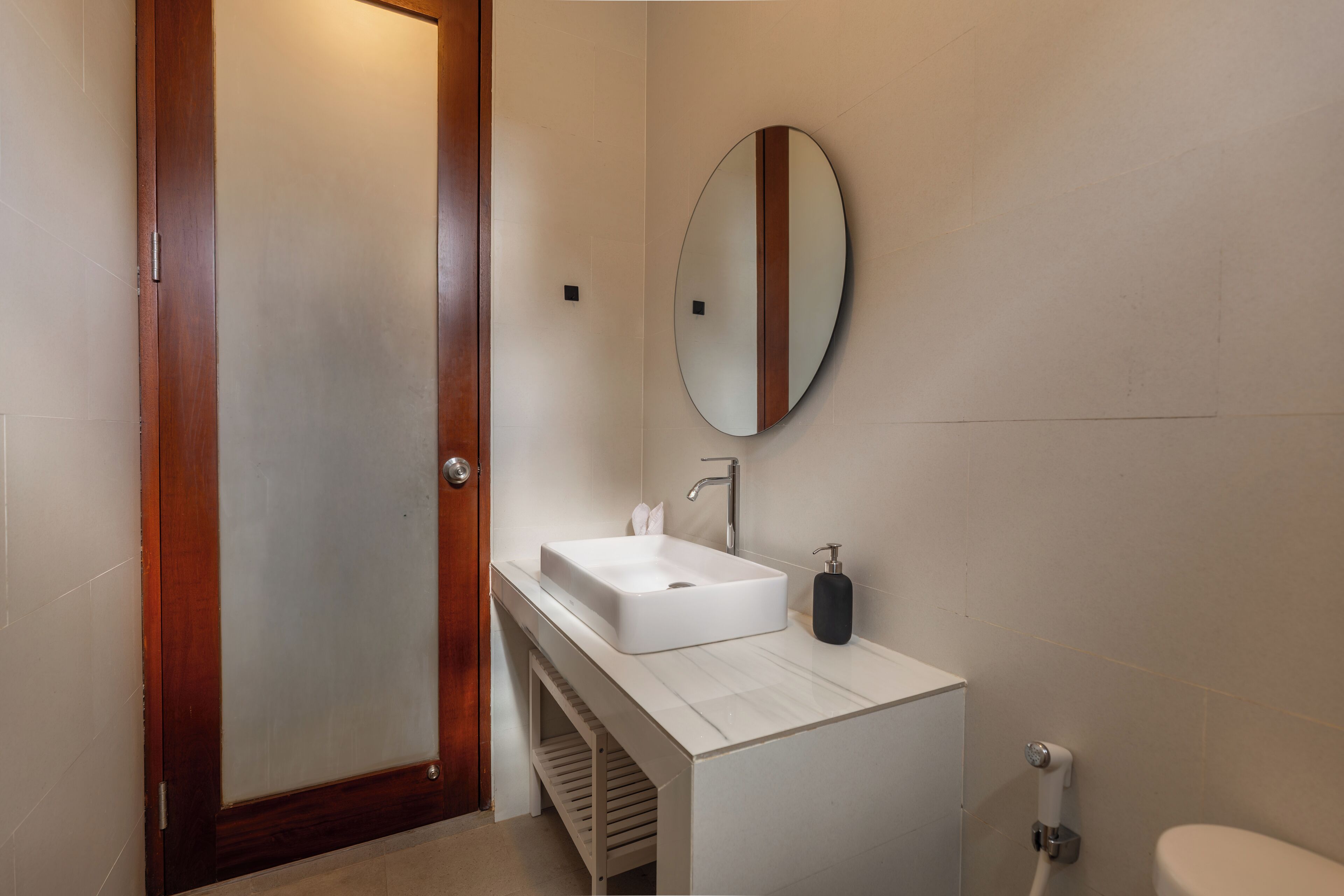 A bathroom with a white sink, a mirror, and a toilet.