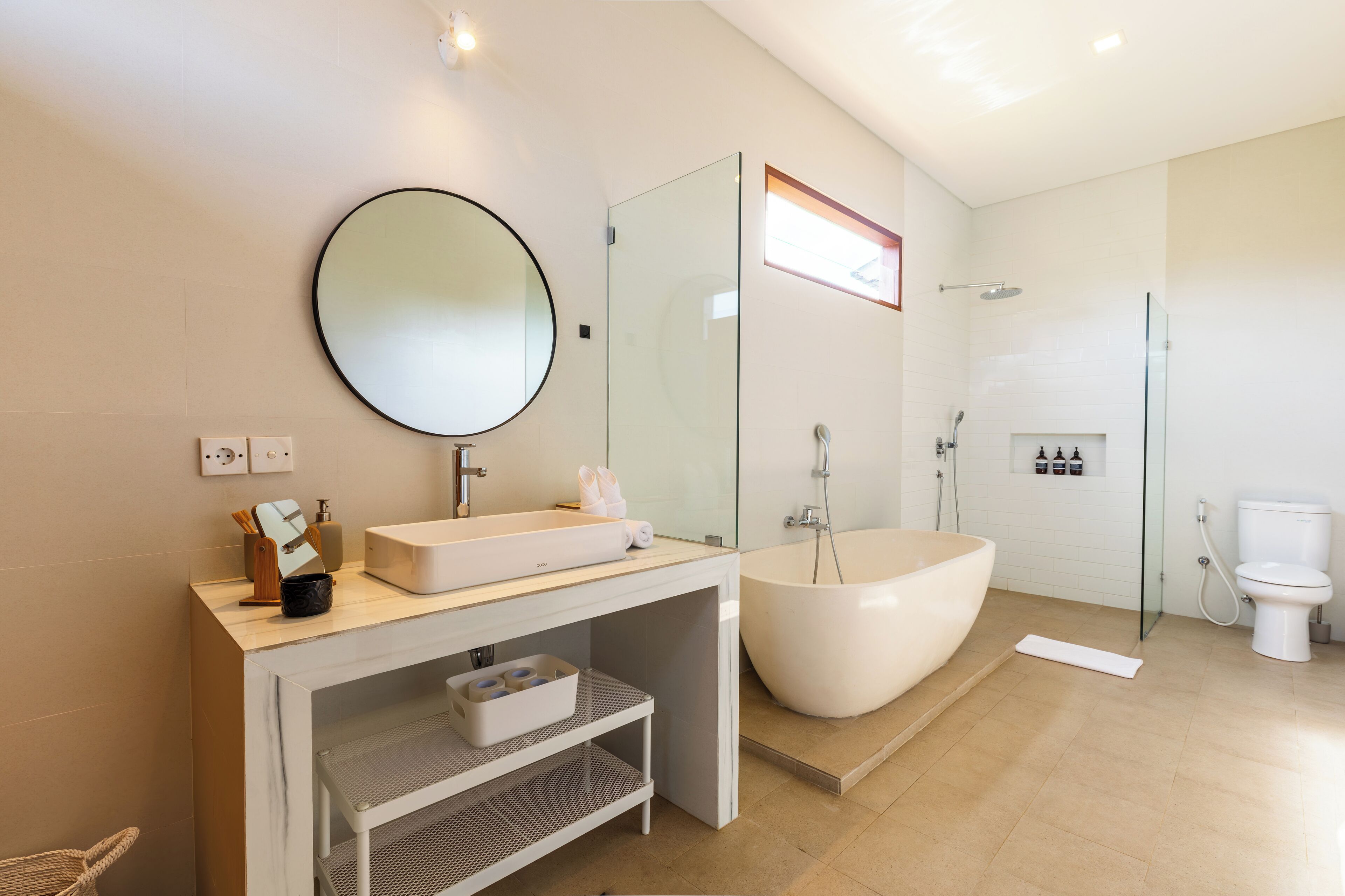 Ein modernes Badezimmer mit einer freistehenden Badewanne, einem runden Spiegel und einer Duschkabine.