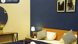 A hotel room with a bed, a bedside table, a lamp, and a tray with toiletries.