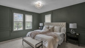 A bedroom with a tufted headboard, a bench, two bedside tables with lamps, and a chandelier. - Downtown, Historic, Newly Renovated (Raleigh)
