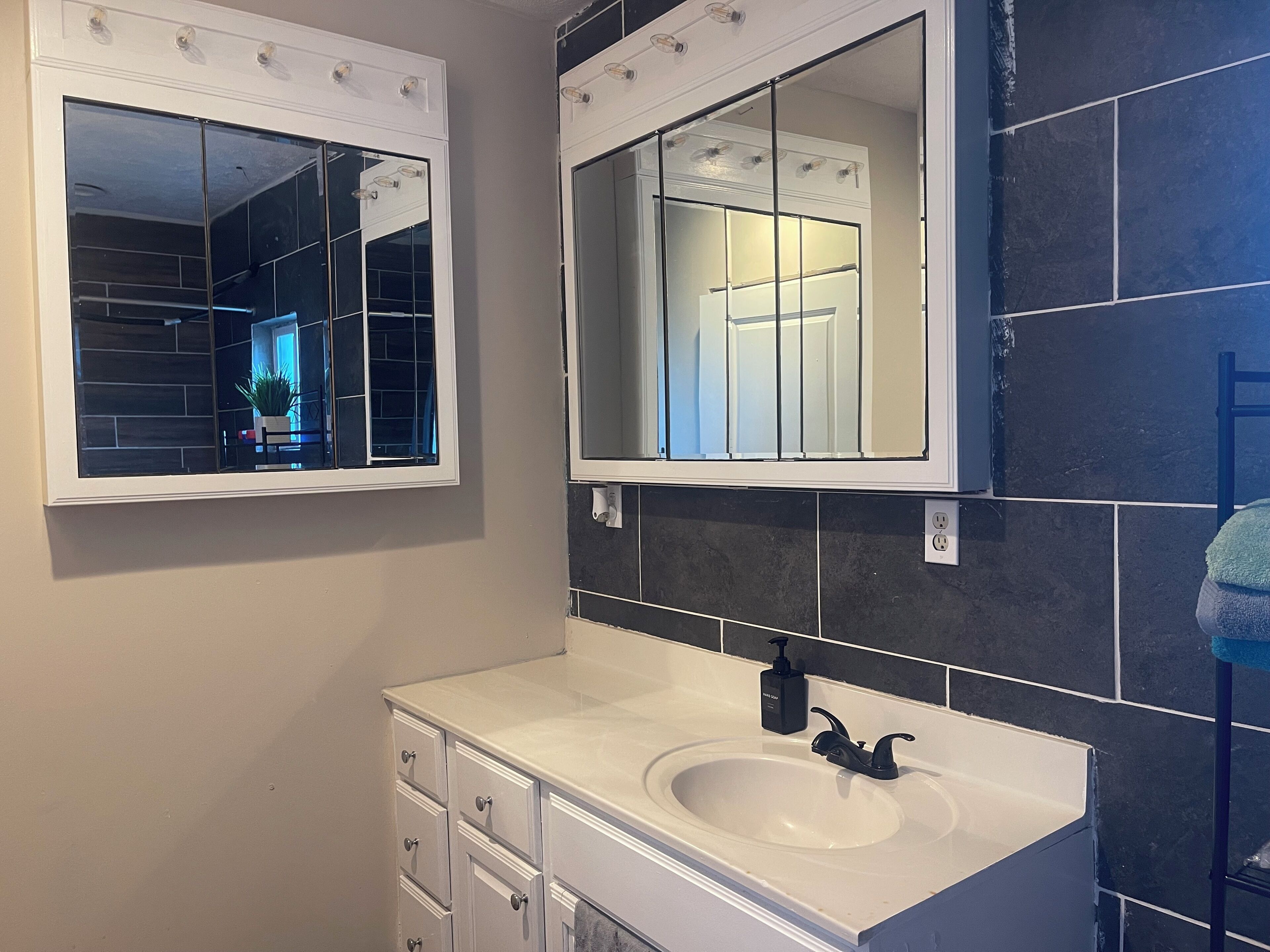 A bathroom with a white vanity, a sink, and two mirrors.
