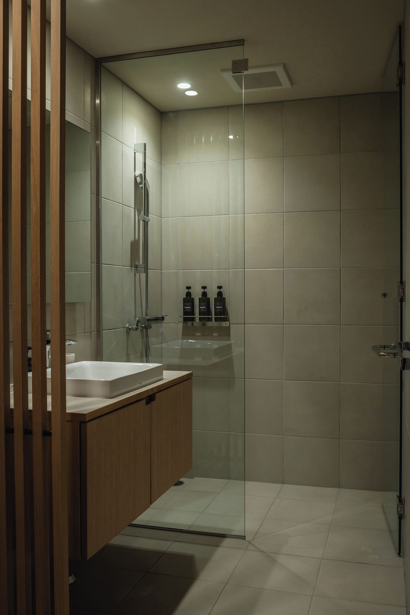 Une salle de bain moderne avec une douche  à parois de verre, un meuble-lavabo en bois et un grand miroir.