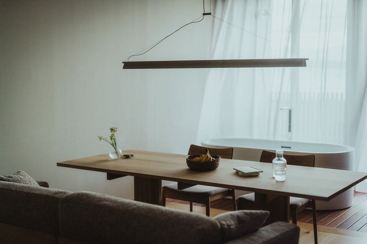 A modern dining area with a wooden table, chairs, and a hanging light fixture.