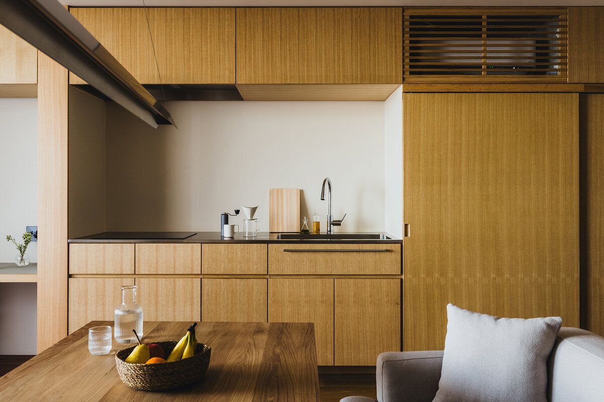 A modern kitchen with wooden cabinets, a black countertop, and a dining area with a table and chairs.