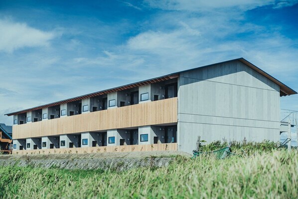 Un edificio moderno de varios pisos con techo plano y una combinación de paneles de hormigón y madera.
