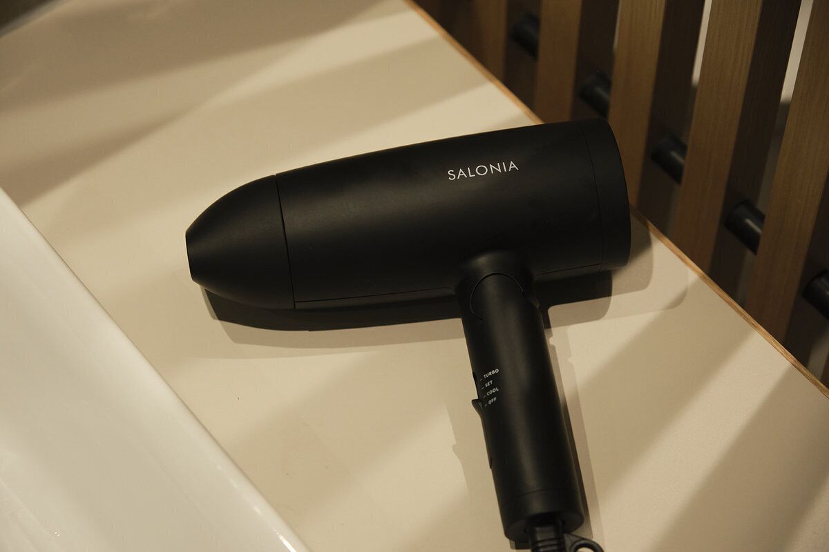 A black hair dryer with the brand name 'SALONIA' on a white countertop.