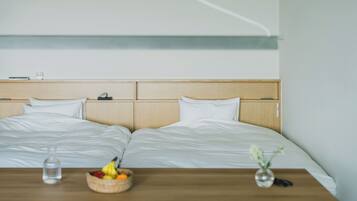 A double bed with a wooden headboard, a bedside table with a fruit bowl and a vase, and a bedside lamp.